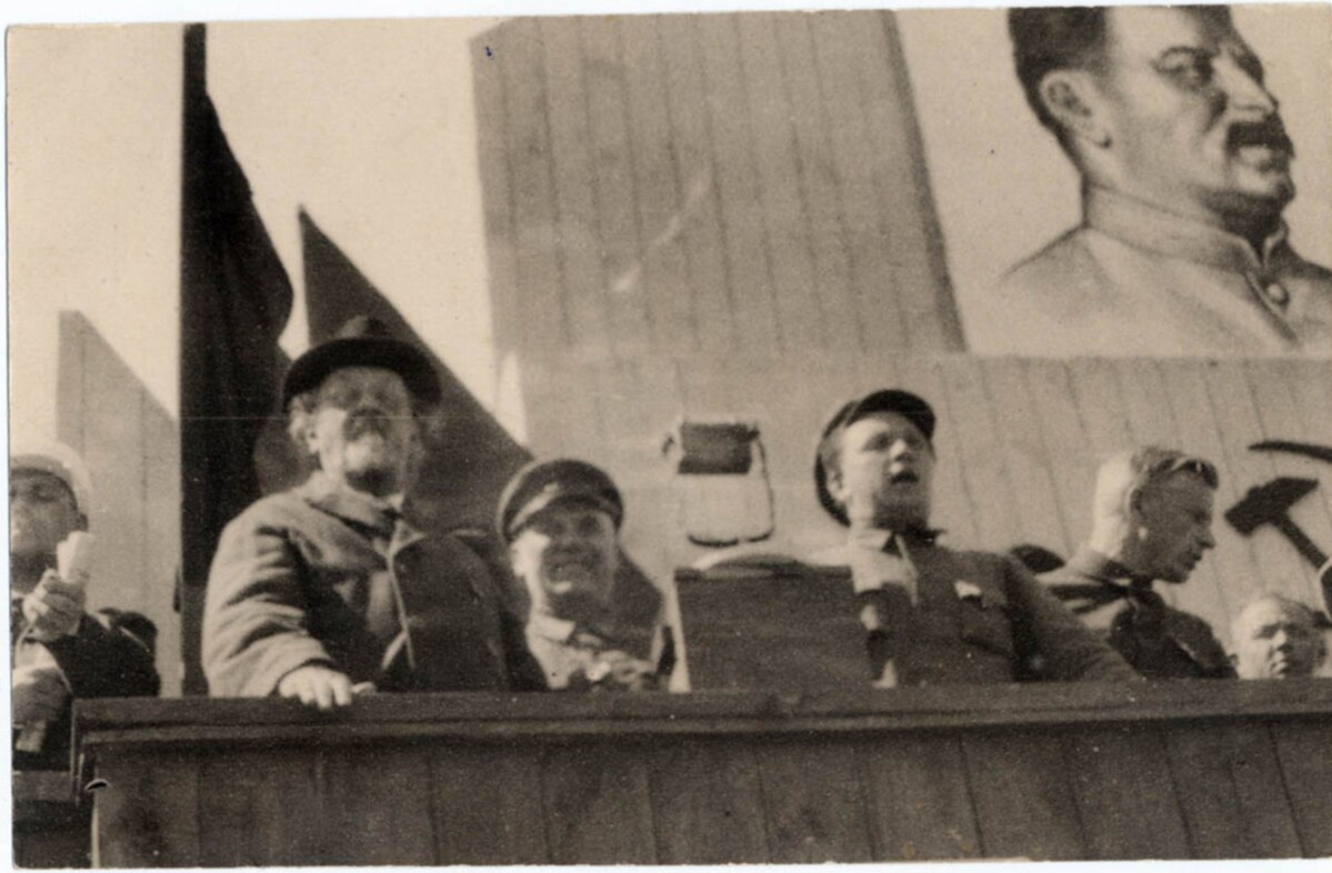 К. Э. Циолковский на трибуне среди советских и партийных работников во время районного Дня Обороны. 1934. Фотограф: Чмиль Феодосий Андроникович (1900-1945). Цифровая копия оригинальной черно-белой фотографии Константина Эдуардовича Циолковского. Источник: Wikimedia Commons (Public Domain).